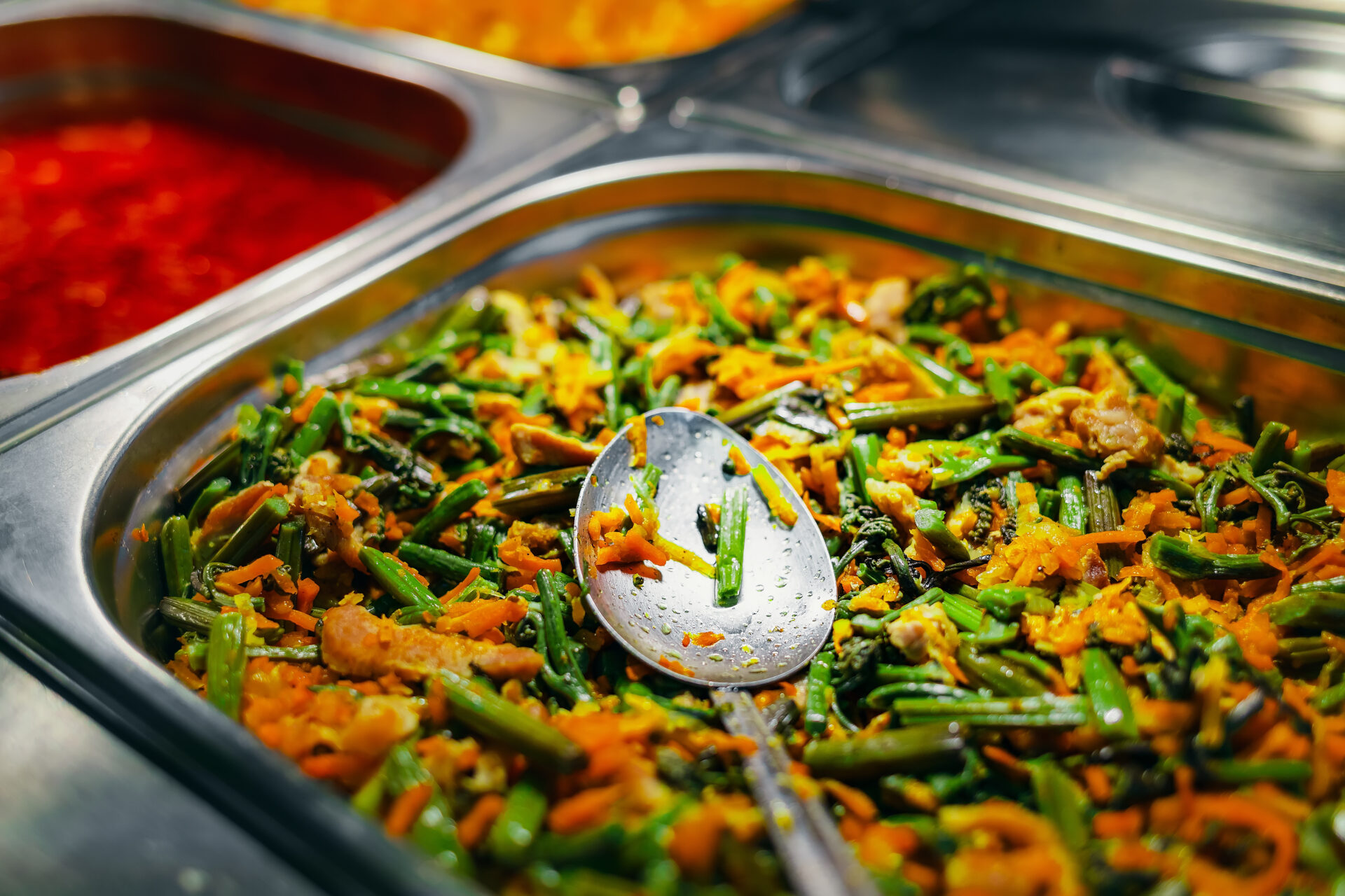 Stewed string beans with carrots in containers in window of public dining room. Concept of public catering. Delicious healthy food. Close-up